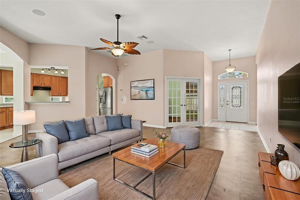 A living room features a grey sofa, a wooden coffee table, and tile flooring — 2852 CAPE HORN COURT, TAVARES, FL