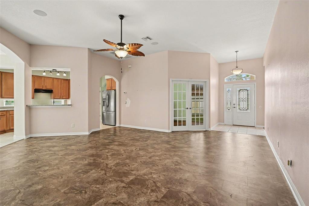 An open living area features brown tile flooring, a ceiling fan, and white French doors — 2852 CAPE HORN COURT, TAVARES, FL