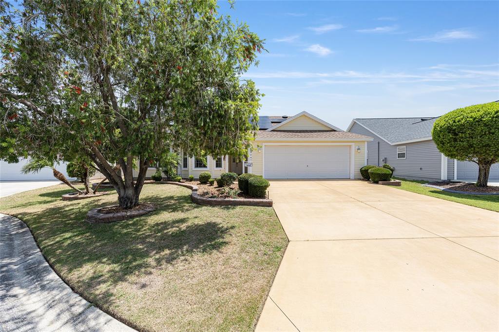A single-story house with a yellow exterior, a two-car garage, and a large front tree — 2047 DUNSTER COURT, THE VILLAGES, FL