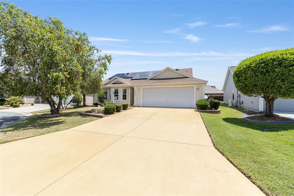 A yellow single-story house with a two-car garage and solar panels on the roof — 2047 DUNSTER COURT, THE VILLAGES, FL