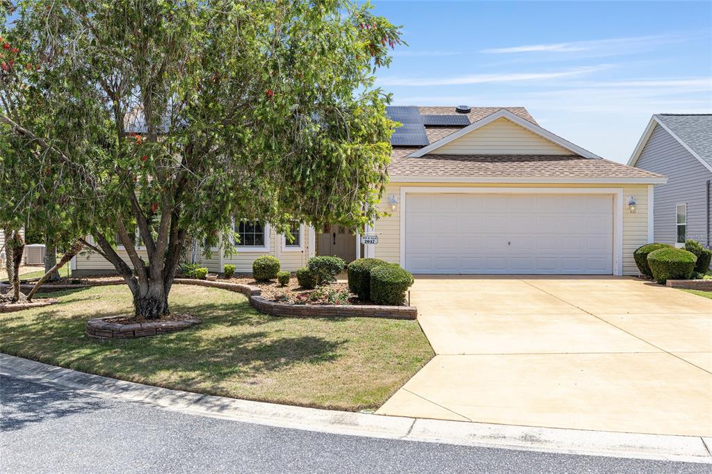 A yellow single-story house with a two-car garage, solar panels, and a landscaped front yard — 2047 DUNSTER COURT, THE VILLAGES, FL