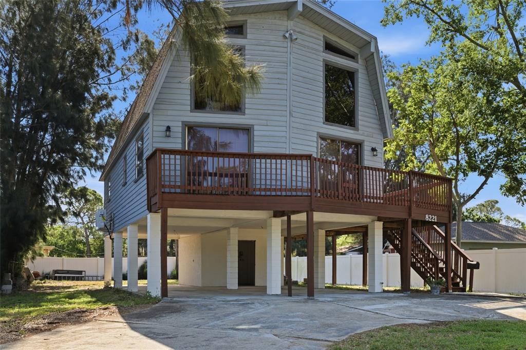 A two-story house with light blue siding is elevated on white concrete pillars — 8221 RIVERSIDE DR NE, ST PETERSBURG, FL