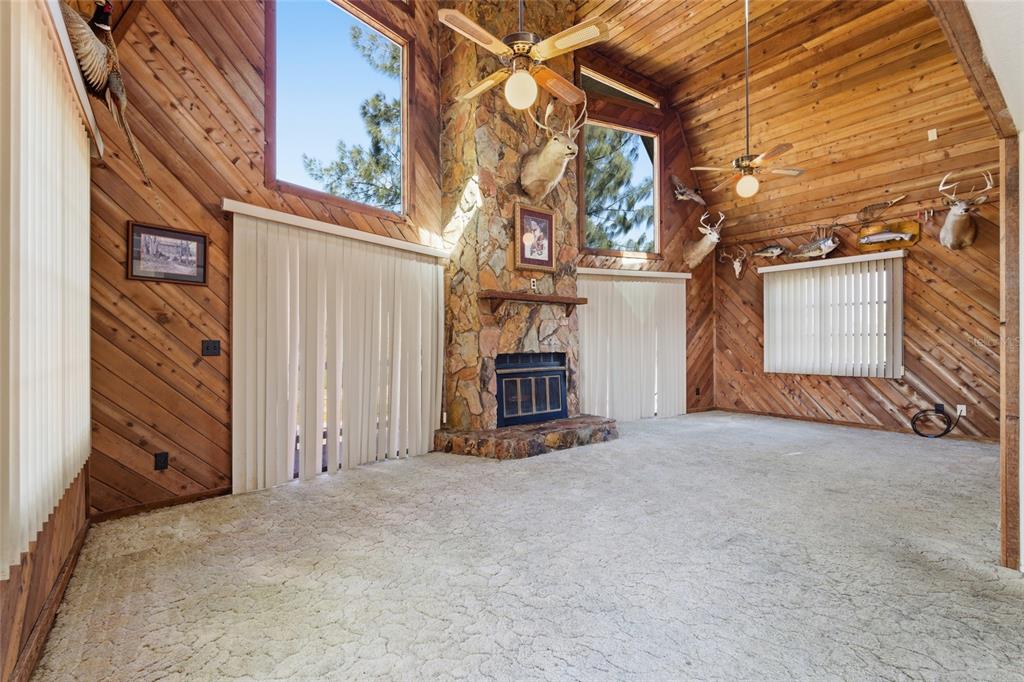 A living room features wood-paneled walls, a stone fireplace, and multiple taxidermy animal mounts — 8221 RIVERSIDE DR NE, ST PETERSBURG, FL