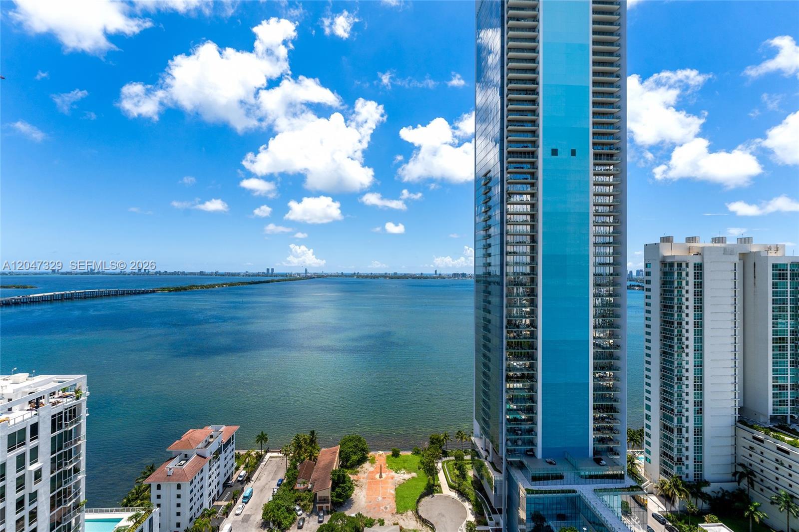 An aerial view shows a tall glass skyscraper overlooking a large body of water — 600 NE 27th St # 2904, Miami FL 33137, MIAMI, FL
