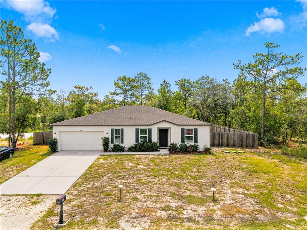 A single-story house with a white exterior, a two-car garage, and a large front yard — 15186 DUCK HAWK ROAD, WEEKI WACHEE, FL