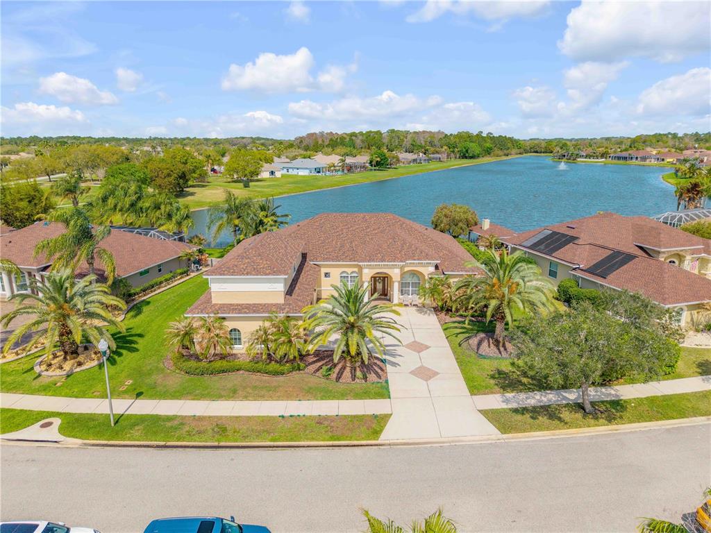 An aerial view shows a single-story house with a brown roof near a lake — 3377 CATERINA DRIVE, NEW SMYRNA BEACH, FL