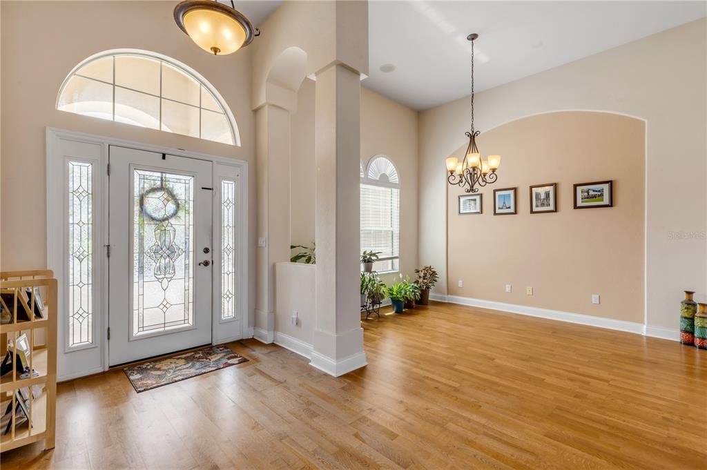 A bright foyer and dining area feature hardwood floors, high ceilings, and a decorative chandelier — 3377 CATERINA DRIVE, NEW SMYRNA BEACH, FL