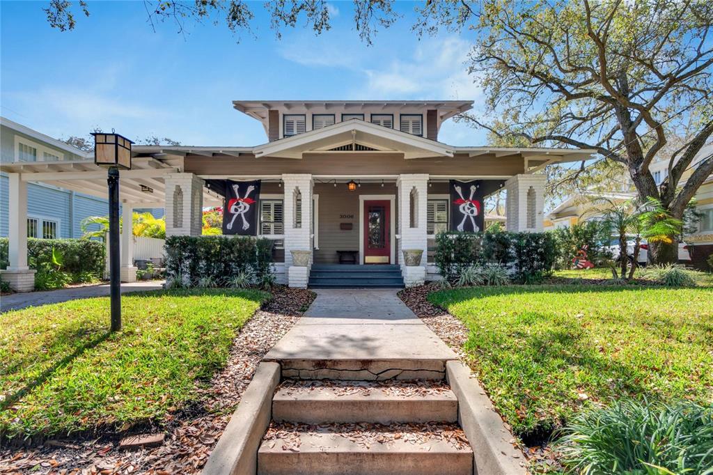 A single-story bungalow with a front porch, white columns, and two pirate flags hanging outside — 3006 W HARBOR VIEW AVENUE, TAMPA, FL