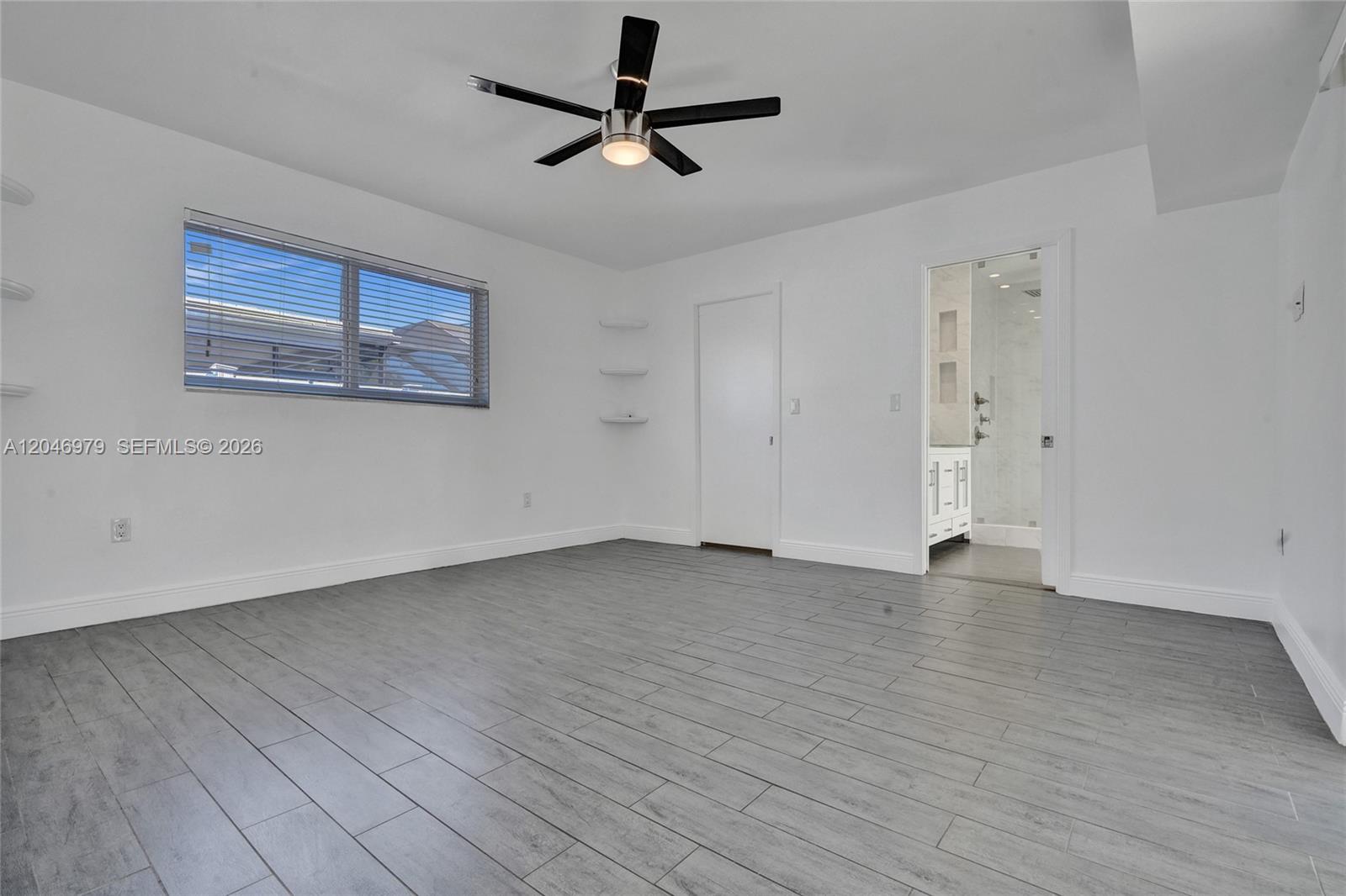 A bedroom with gray wood-look tile flooring, a ceiling fan, and an attached bathroom — 9240 54th St, Cooper City FL 33328, COOPER CITY, FL