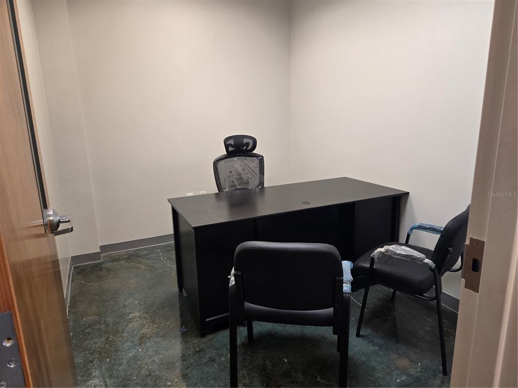 A small office features a black desk, three chairs, and a dark concrete floor — 14202 N NEBRASKA AVENUE UNIT 14202, TAMPA, FL
