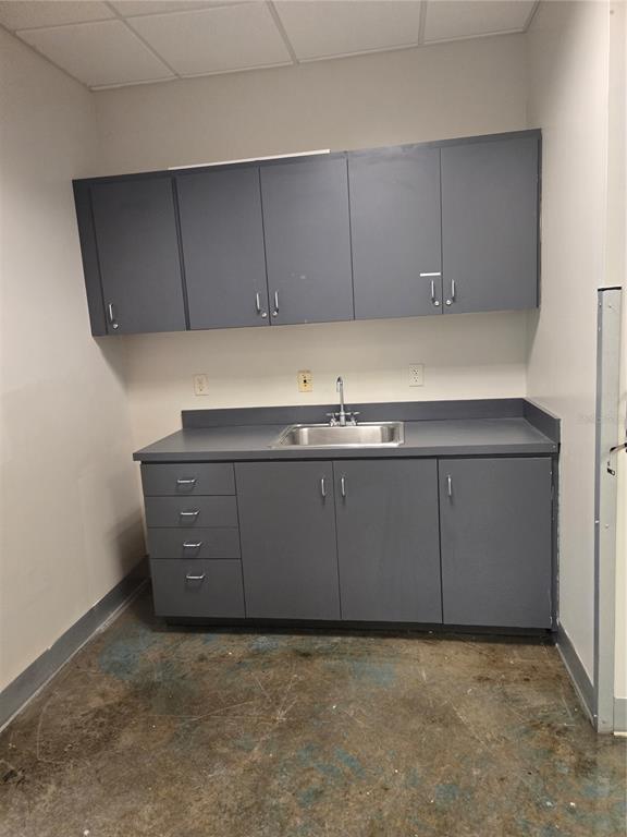 A utility room features grey cabinets, a stainless steel sink, and a concrete floor — 14202 N NEBRASKA AVENUE UNIT 14202, TAMPA, FL