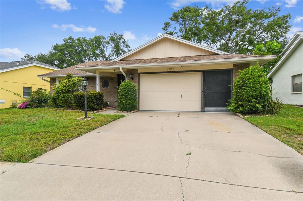 A single-story house with a beige garage door, brick accents, and a concrete driveway — 13127 TOPFLITE COURT, HUDSON, FL