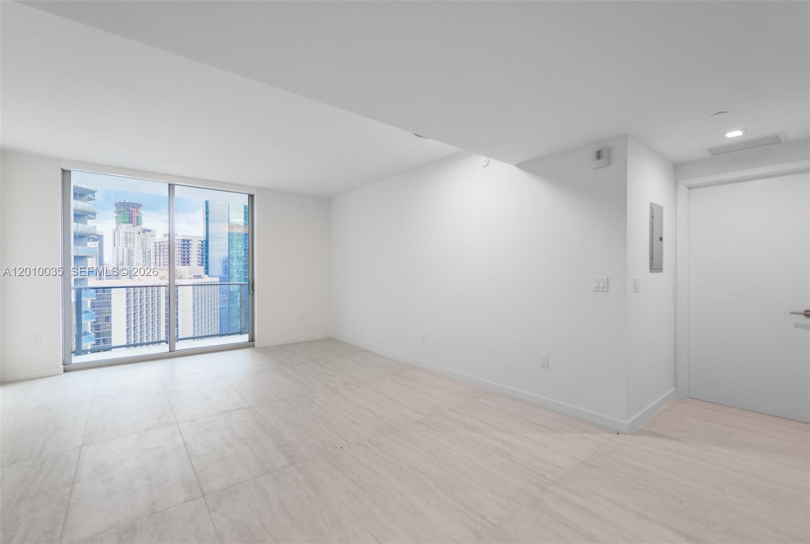 An empty room with white walls, light tile flooring, and a sliding glass balcony door — 77 SE 5 Street # 2603, Miami FL 33131, MIAMI, FL