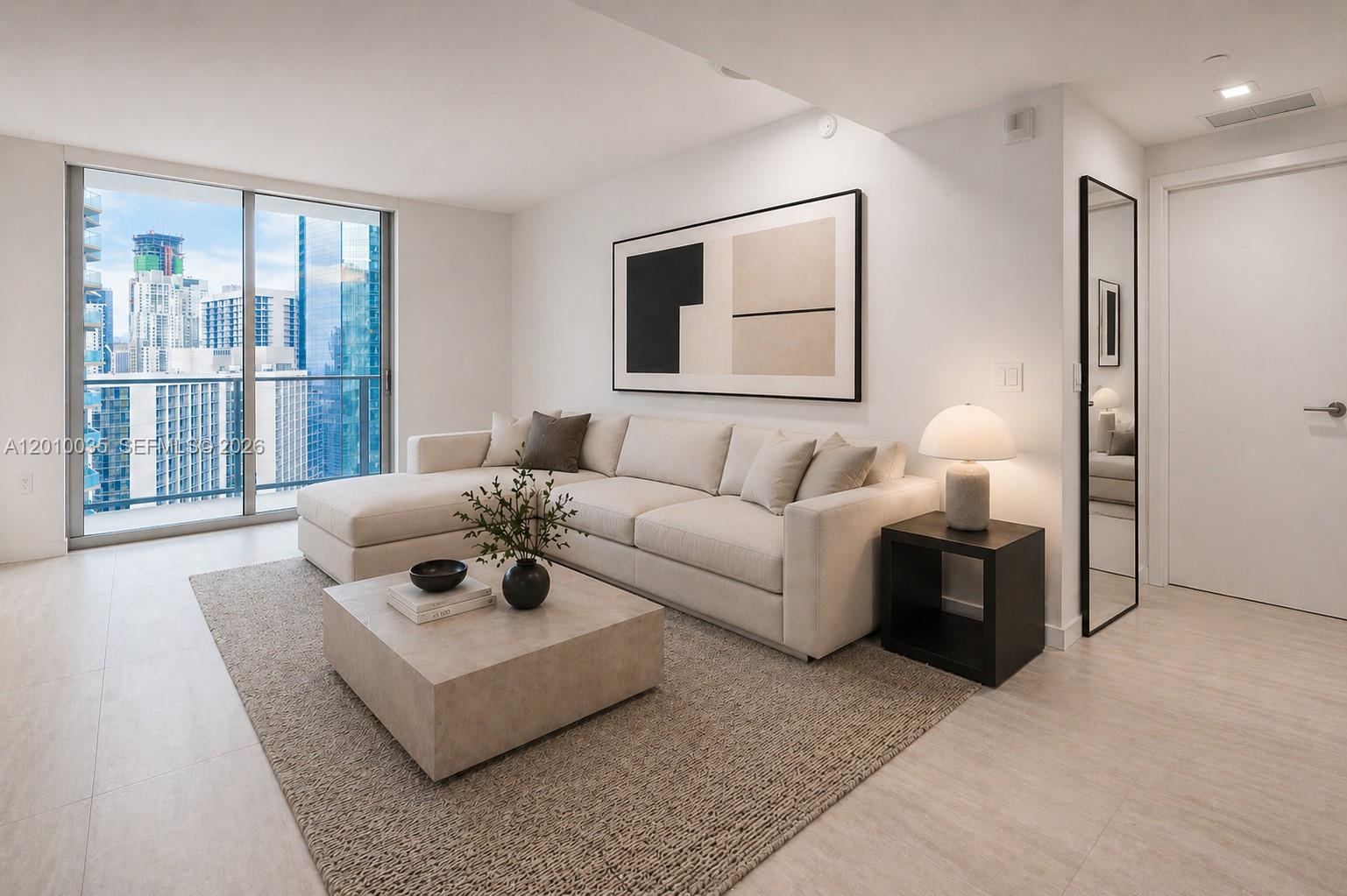 A modern living room features a beige sectional sofa, a square coffee table, and city views — 77 SE 5 Street # 2603, Miami FL 33131, MIAMI, FL