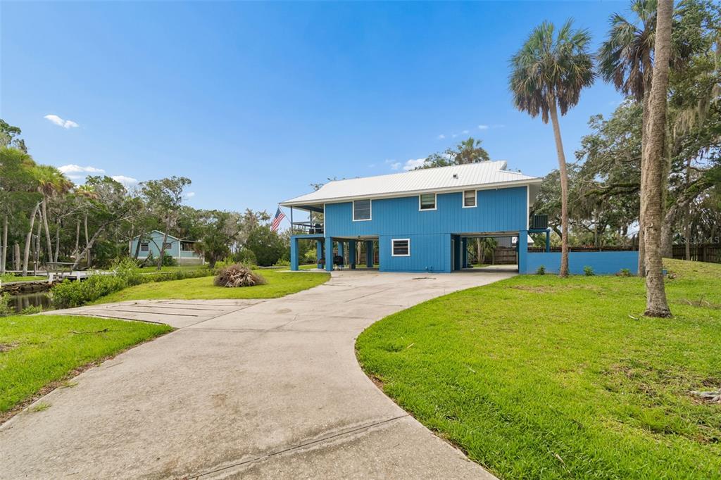 An elevated blue house with a metal roof and a wraparound deck stands on stilts — 1455 S OZELLO TRAIL, CRYSTAL RIVER, FL