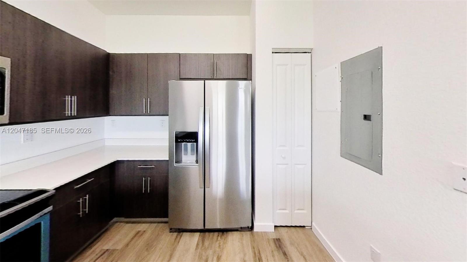 A kitchen features dark wood cabinets, stainless steel appliances, white countertops, and light wood flooring — 15650 SW 136th St # 207, Miami FL 33196, MIAMI, FL