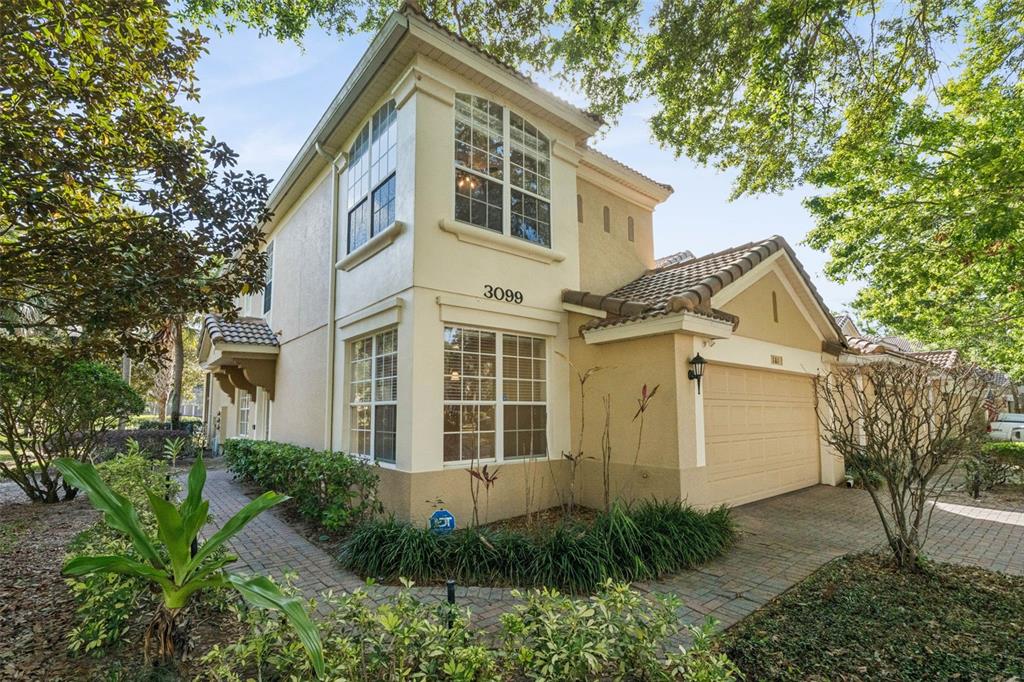 A two-story stucco house features a tan exterior, a paved driveway, and a garage — 3099 METRO SEVILLA DRIVE UNIT 101, ORLANDO, FL