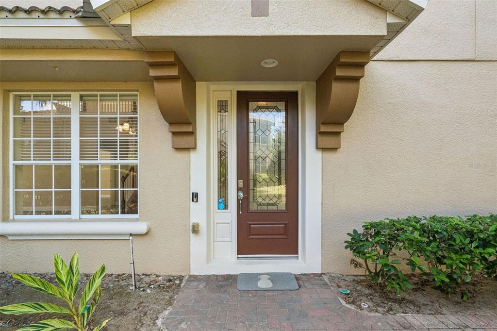 A brown front door with a glass insert sits under a covered entryway — 3099 METRO SEVILLA DRIVE UNIT 101, ORLANDO, FL