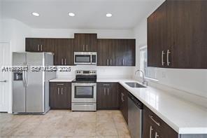 A kitchen features dark wood cabinets, stainless steel appliances, and white countertops — 1121 NW 41st Ln, Lauderhill FL 33313, LAUDERHILL, FL