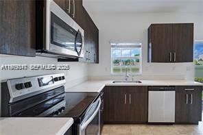 A kitchen features dark wood cabinets, stainless steel appliances, and white countertops — 1121 NW 41st Ln, Lauderhill FL 33313, LAUDERHILL, FL