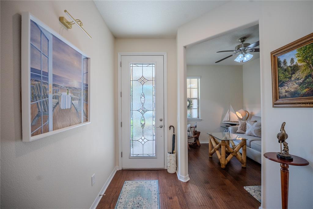 An entryway with wood floors, a glass-paneled door, and an adjacent room with a ceiling fan — 7676 SW 94TH CIRCLE, OCALA, FL