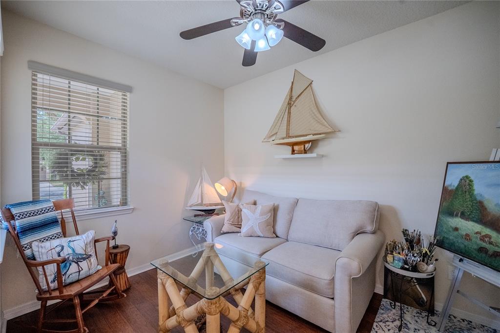 A small living room features a beige sofa, a glass-topped bamboo table, and nautical decor — 7676 SW 94TH CIRCLE, OCALA, FL