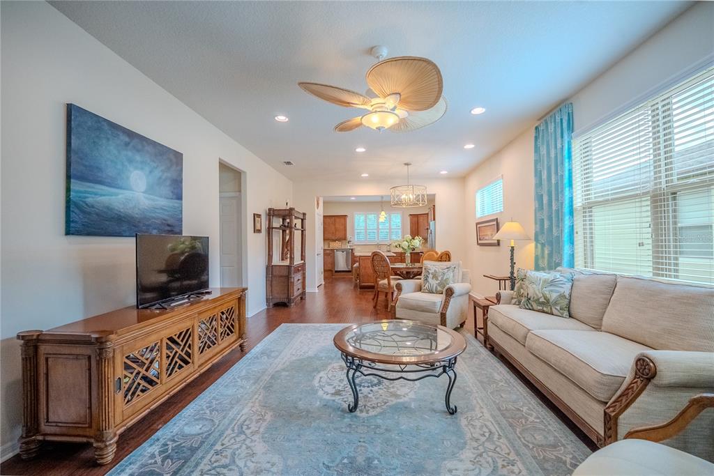 A living room features a wooden media console, a beige sofa, and a ceiling fan — 7676 SW 94TH CIRCLE, OCALA, FL