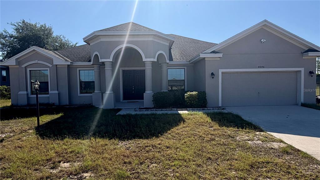 A single-story house with a gray stucco exterior, arched entryway, and a two-car garage — 4046 DINNER LAKE WAY, LAKE WALES, FL