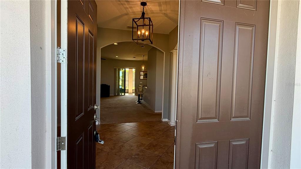 An open front door reveals a tiled entryway leading into a carpeted living area — 4046 DINNER LAKE WAY, LAKE WALES, FL