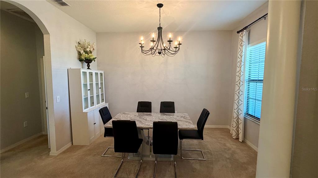 A dining room features a marble-topped table, black chairs, a chandelier, and a white hutch — 4046 DINNER LAKE WAY, LAKE WALES, FL