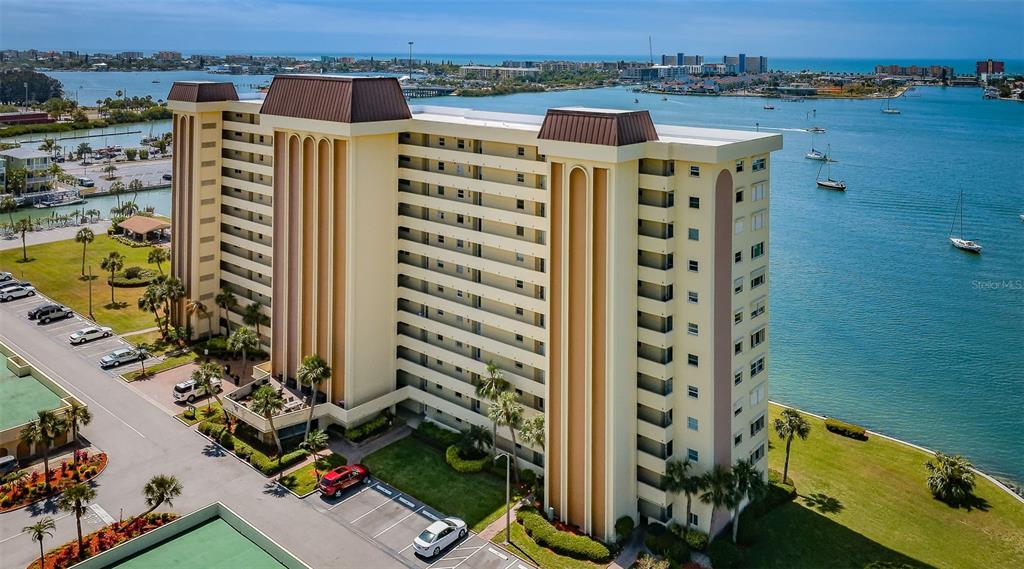 An aerial view of a multi-story apartment building situated along a waterfront with boats — 4525 COVE CIRCLE UNIT 604, ST PETERSBURG, FL