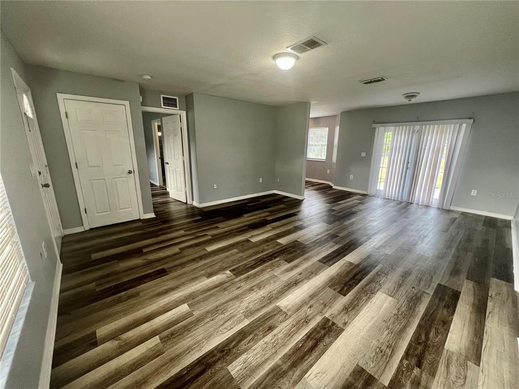 An open-concept living area features gray walls, wood-look plank flooring, and sliding glass doors — 45 PINE CIRCLE, OCALA, FL