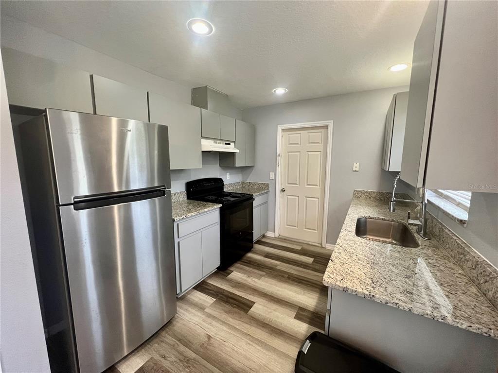 A kitchen features gray cabinets, granite countertops, stainless steel appliances, and wood-look flooring — 45 PINE CIRCLE, OCALA, FL