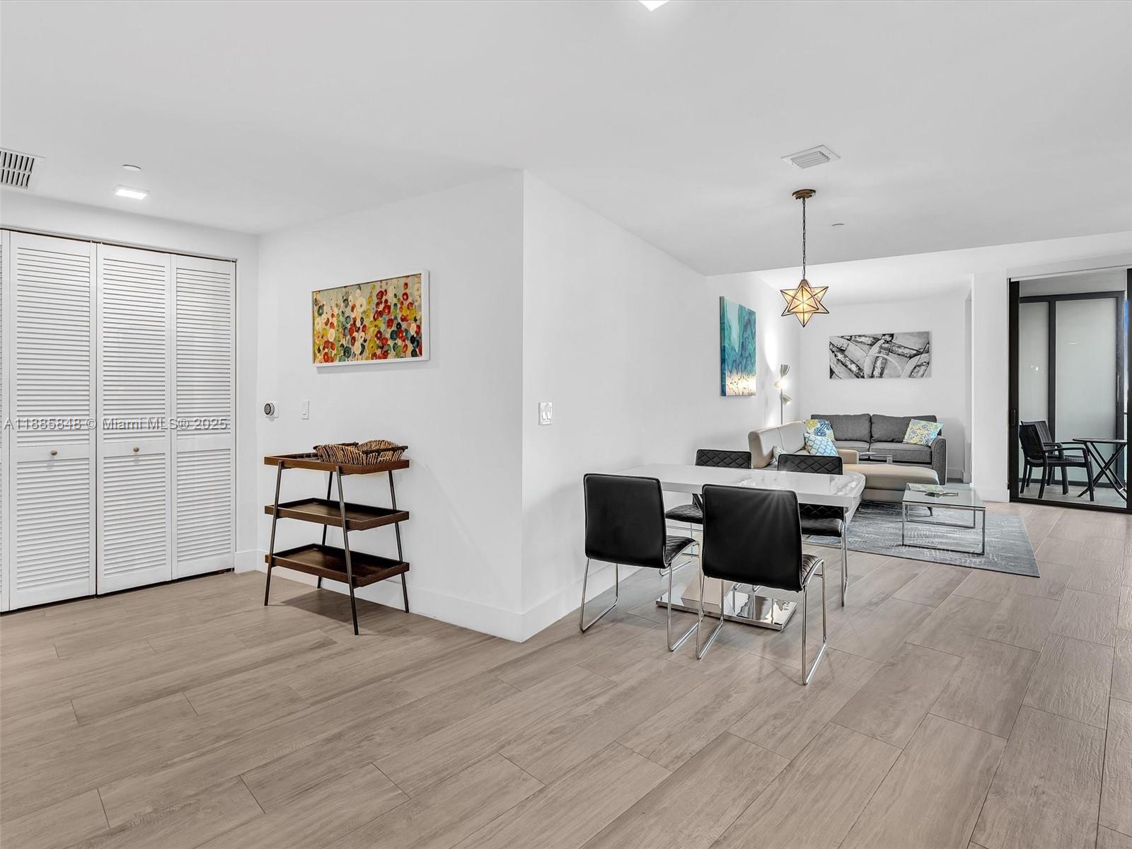 A dining area with a modern table and chairs sits adjacent to a living room — 121 NE 34th St # 3114, Miami FL 33137, MIAMI, FL