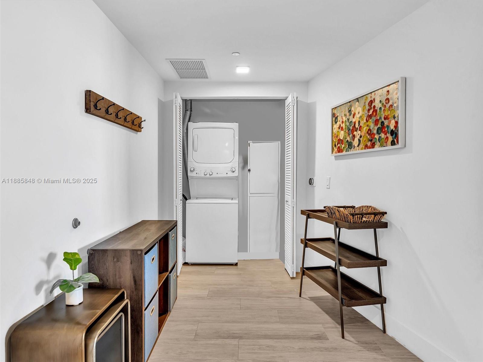 A laundry room features a stacked washer and dryer, shelving units, and a coat rack — 121 NE 34th St # 3114, Miami FL 33137, MIAMI, FL