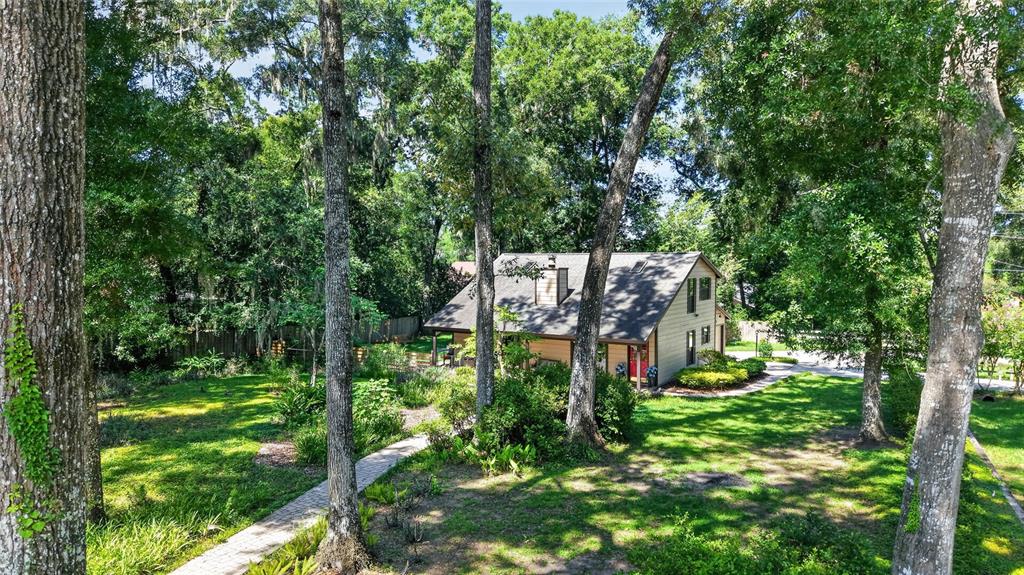 An elevated view of a house with a gray roof surrounded by many tall trees — 3936 SE 23RD TERRACE, OCALA, FL