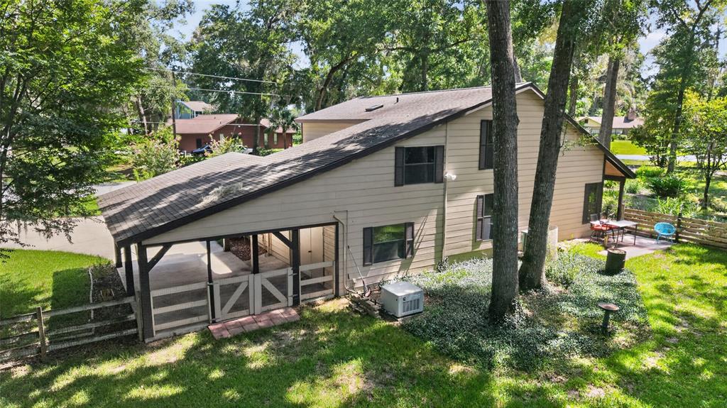An exterior view of a two-story house with a screened-in carport and a grassy yard — 3936 SE 23RD TERRACE, OCALA, FL