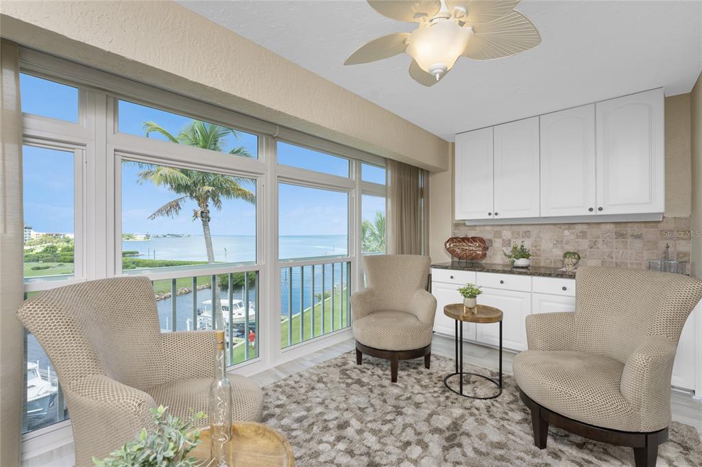 A sunroom with three armchairs, a rug, white cabinetry, and a view of the water — 1250 W MARION AVENUE UNIT 242, PUNTA GORDA, FL