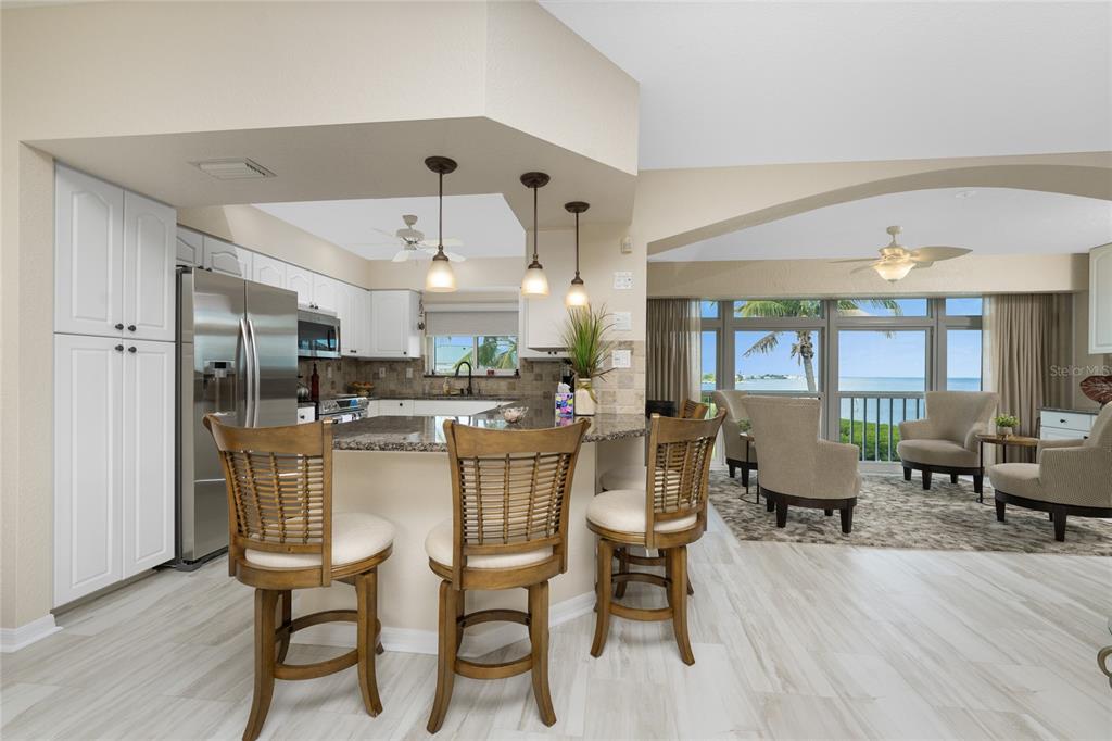 A kitchen with a breakfast bar and stools opens into a living area overlooking water — 1250 W MARION AVENUE UNIT 242, PUNTA GORDA, FL