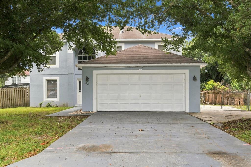 A two-story house with a blue exterior, a white garage door, and a concrete driveway — 621 JUILLAC WAY, KISSIMMEE, FL