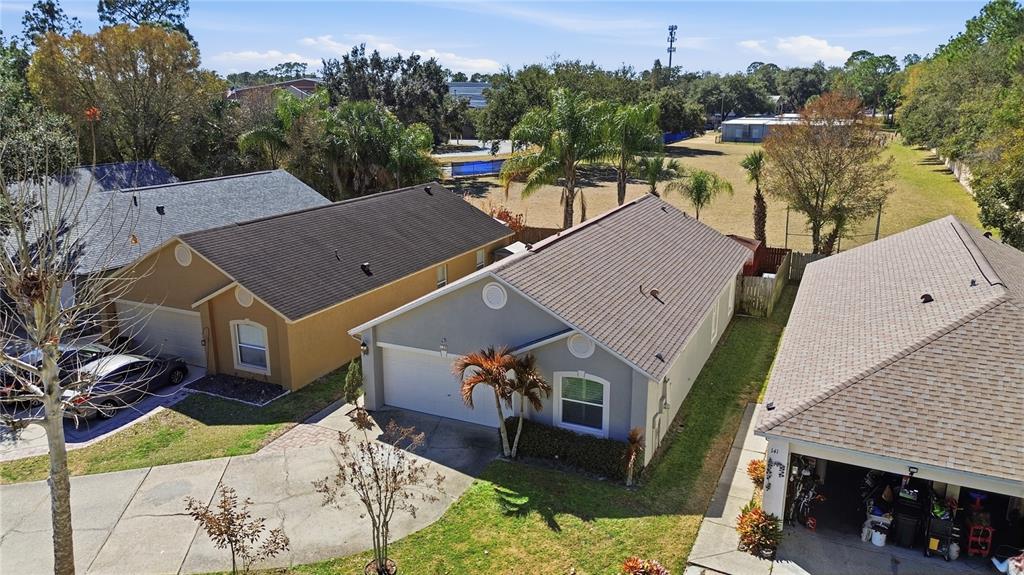 An aerial view shows three suburban houses with shingled roofs and driveways in a neighborhood — 139 PLACID WOODS COURT, SANFORD, FL