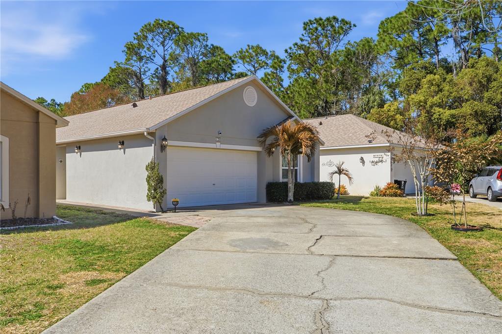 A single-story house with a beige stucco exterior, a two-car garage, and a concrete driveway — 139 PLACID WOODS COURT, SANFORD, FL