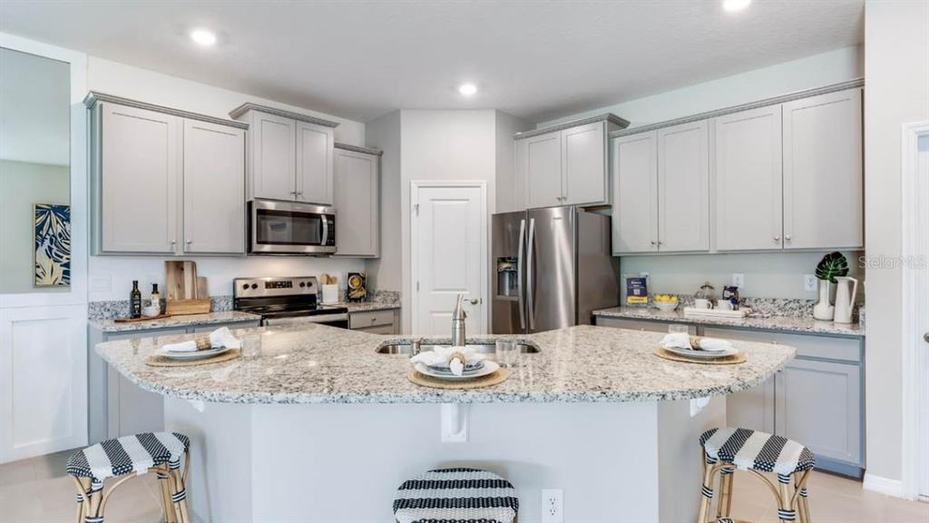 A kitchen with light gray cabinets, granite countertops, a central island, and stainless steel appliances — 6245 PARMERON LANE, SARASOTA, FL
