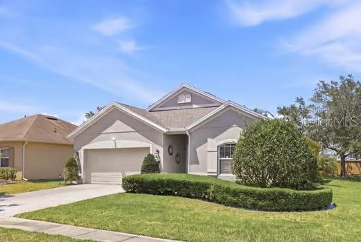 A single-story house with a light-colored stucco exterior, a two-car garage, and a manicured hedge — 2825 RUNNING BROOK CIRCLE, KISSIMMEE, FL