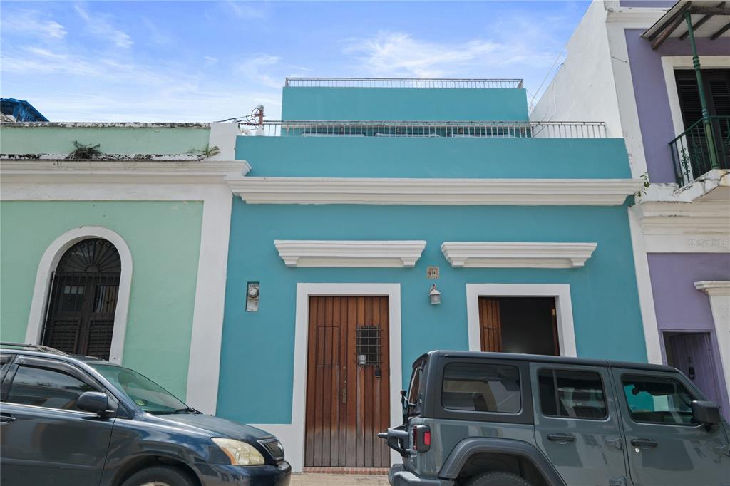 A teal-colored house exterior features a wooden door and a rooftop terrace with metal railings — 10 CALLE SOL, OLD SAN JUAN, PR