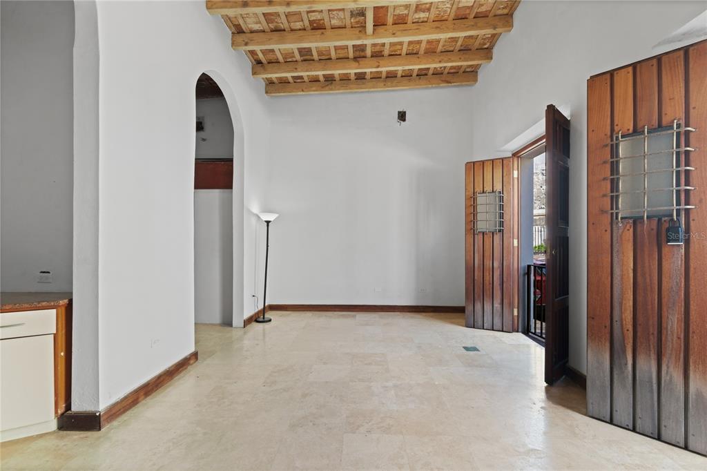 An interior room features a wood-beamed ceiling, stone tile flooring, and arched doorways — 10 CALLE SOL, OLD SAN JUAN, PR