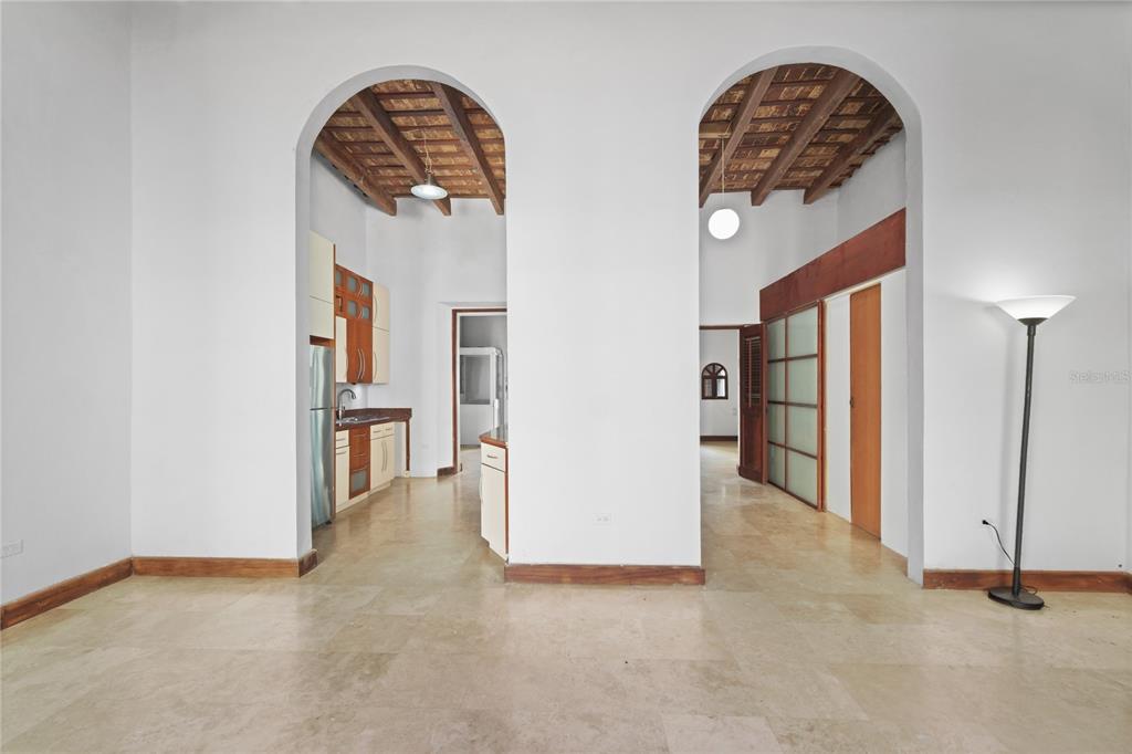 An interior view shows two arched openings leading to a kitchen and hallway with tiled floors — 10 CALLE SOL, OLD SAN JUAN, PR