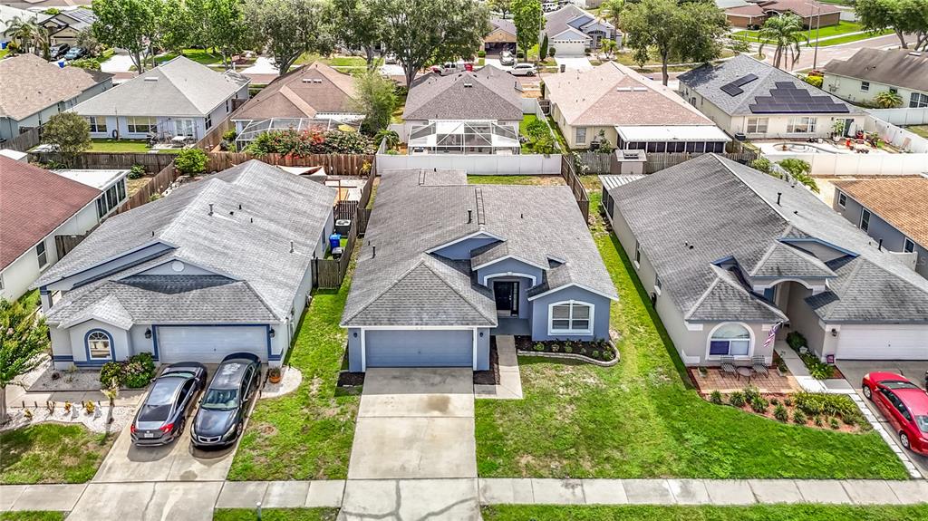 An aerial view shows three suburban houses with gray roofs and driveways in a neighborhood — 1732 HULETT DRIVE, BRANDON, FL