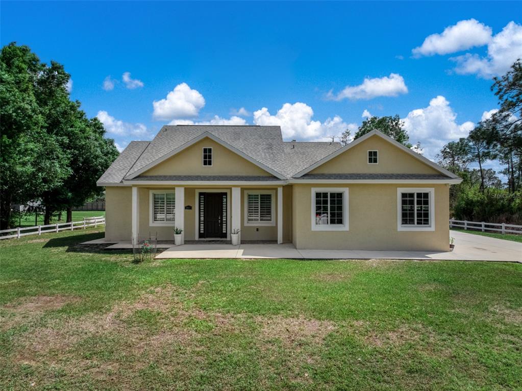 A single-story house with a tan stucco exterior, a dark front door, and a concrete walkway — 2009 FLOWER TERRACE, SEBRING, FL