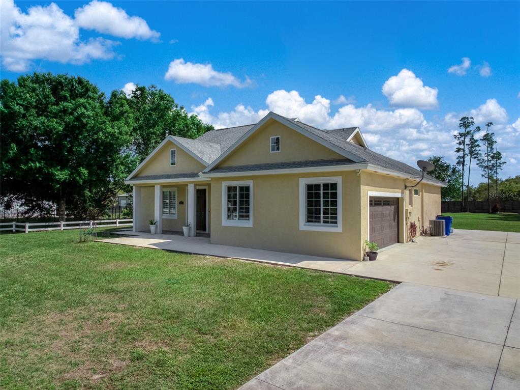 A yellow single-story house with a front porch, attached garage, and a concrete driveway — 2009 FLOWER TERRACE, SEBRING, FL
